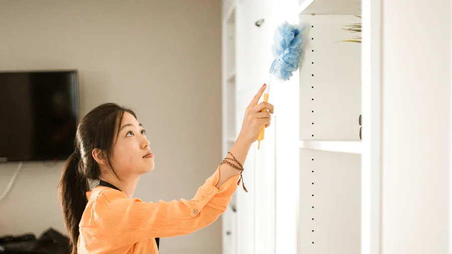 Cleaner dusting a white built-in shelf during recurring house cleaning in Naperville